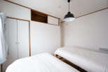 This minimalist bedroom features two twin beds with crisp white linens, perfect for a restful night's sleep.