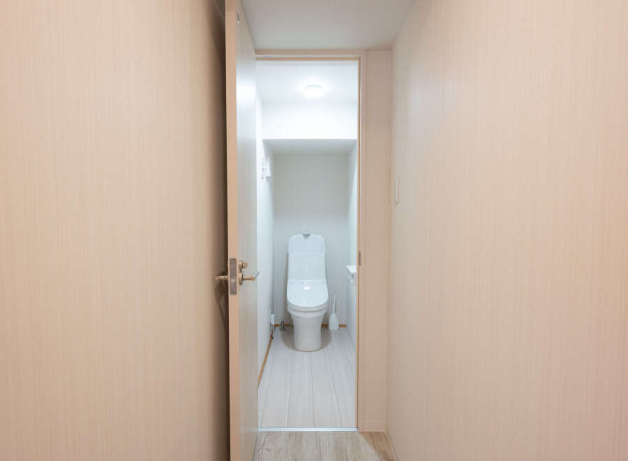 Modern and clean bathroom with a toilet and light wood walls.