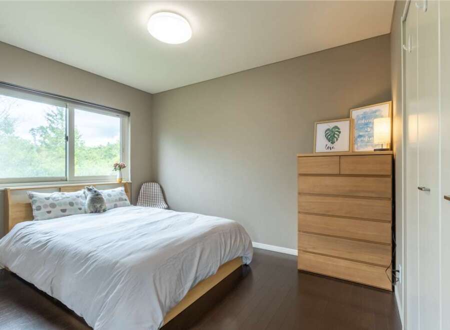 This bedroom boasts a serene atmosphere with its light color palette and large window offering ample natural light.