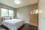 This bedroom boasts a serene atmosphere with its light color palette and large window offering ample natural light.