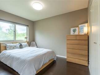 This bedroom boasts a serene atmosphere with its light color palette and large window offering ample natural light.