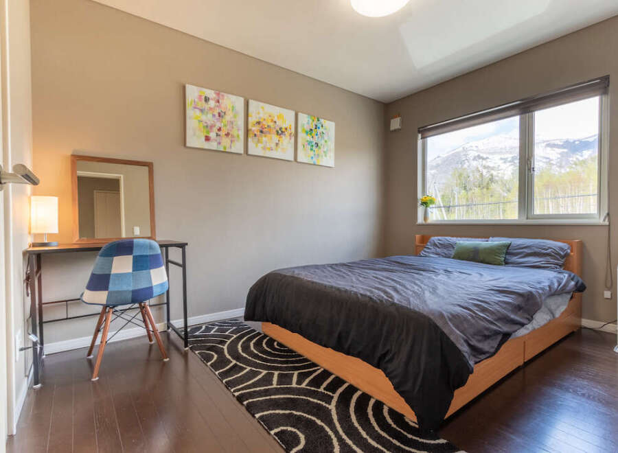 This cozy bedroom features a comfortable double bed, a convenient workspace with a desk and chair, and stunning mountain views from the large window.
