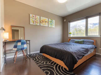 This cozy bedroom features a comfortable double bed, a convenient workspace with a desk and chair, and stunning mountain views from the large window.
