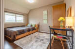 Cozy bedroom with a comfortable bed, a spacious desk perfect for working from home, and plenty of natural light from the large window.