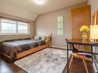 Cozy bedroom with a comfortable bed, a spacious desk perfect for working from home, and plenty of natural light from the large window.