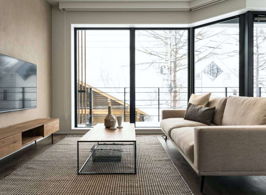 Modern living room with floor-to-ceiling windows offering stunning views of a snowy landscape.
