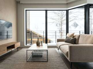 Modern living room with floor-to-ceiling windows offering stunning views of a snowy landscape.