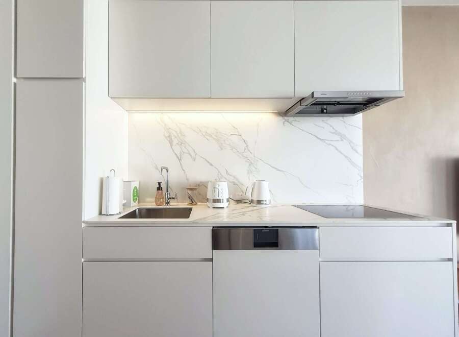 Modern kitchen with white cabinets and marble backsplash.