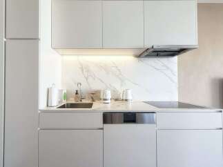 Modern kitchen with white cabinets and marble backsplash.