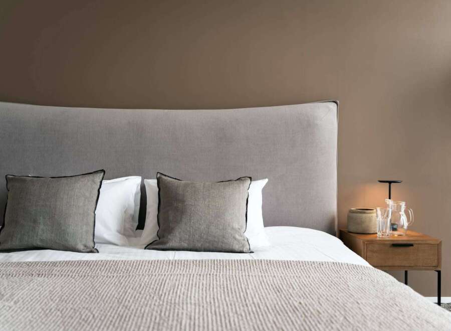 Wake up refreshed in our cozy bedroom, featuring a plush gray headboard and soft linens.