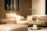 Modern living room with beige sectional sofa and ottoman, complemented by a stylish mirror and floor lamp.