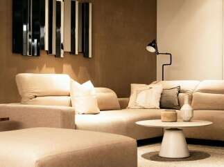 Modern living room with beige sectional sofa and ottoman, complemented by a stylish mirror and floor lamp.