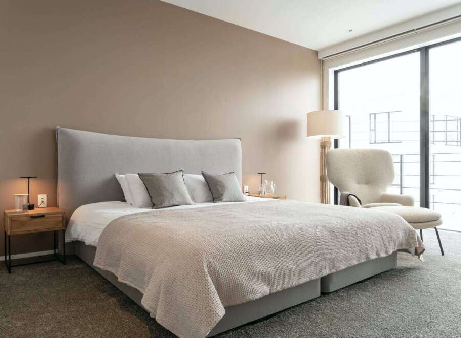 Luxurious bedroom with a king-size bed, plush carpet, and large windows offering stunning views.