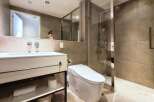 Modern bathroom with sleek white vanity, built-in shelving, and a frameless glass shower enclosure.