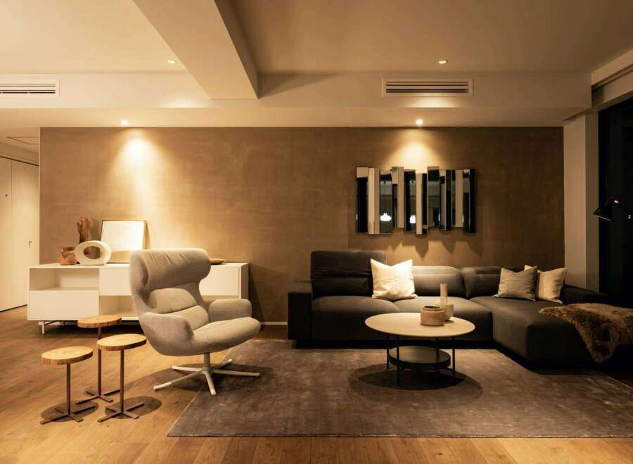 Modern living room with a neutral color palette, featuring a comfortable sectional sofa and a stylish armchair.