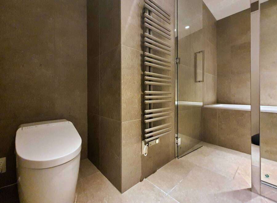 Luxury bathroom boasts a modern toilet, heated towel rack, and a built-in shower bench.