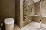 Luxury bathroom boasts a modern toilet, heated towel rack, and a built-in shower bench.