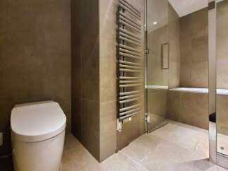 Luxury bathroom boasts a modern toilet, heated towel rack, and a built-in shower bench.