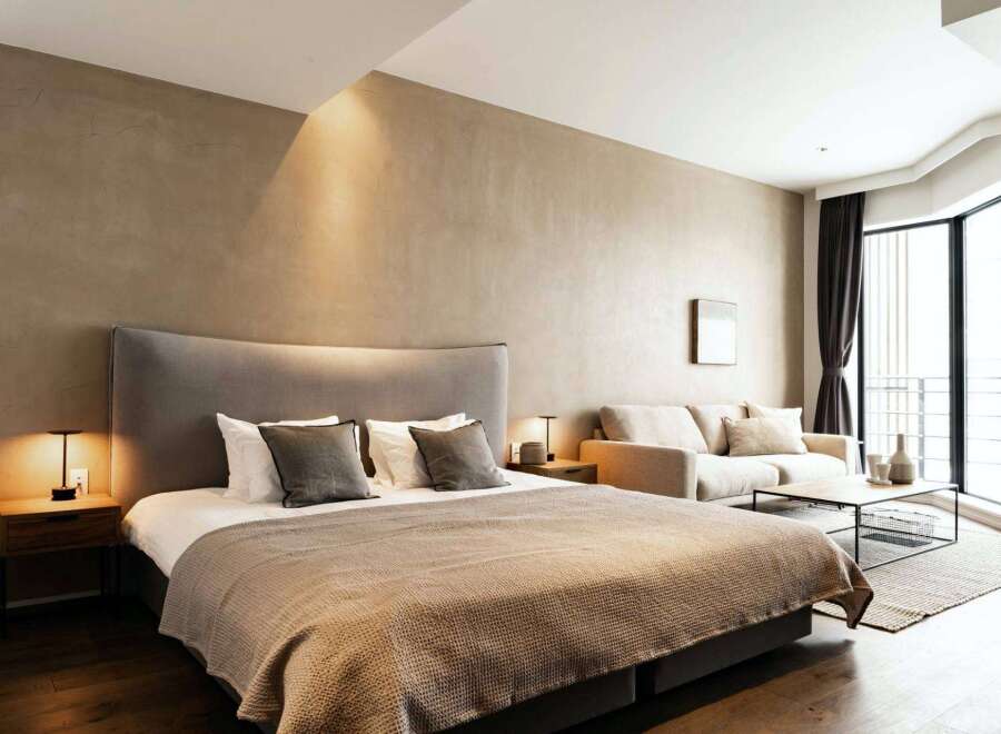 This stunning bedroom boasts a plush king-size bed, a cozy sofa, and large windows offering ample natural light.