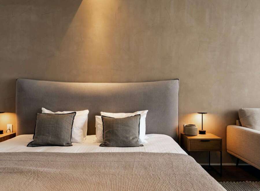 Relax in this serene bedroom, featuring a plush bed with soft linens and a curved headboard.