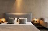 Relax in this serene bedroom, featuring a plush bed with soft linens and a curved headboard.