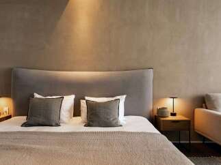 Relax in this serene bedroom, featuring a plush bed with soft linens and a curved headboard.