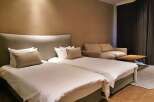 Relax in our stylish hotel room featuring twin beds with plush bedding, a comfortable sofa, and a modern coffee table.