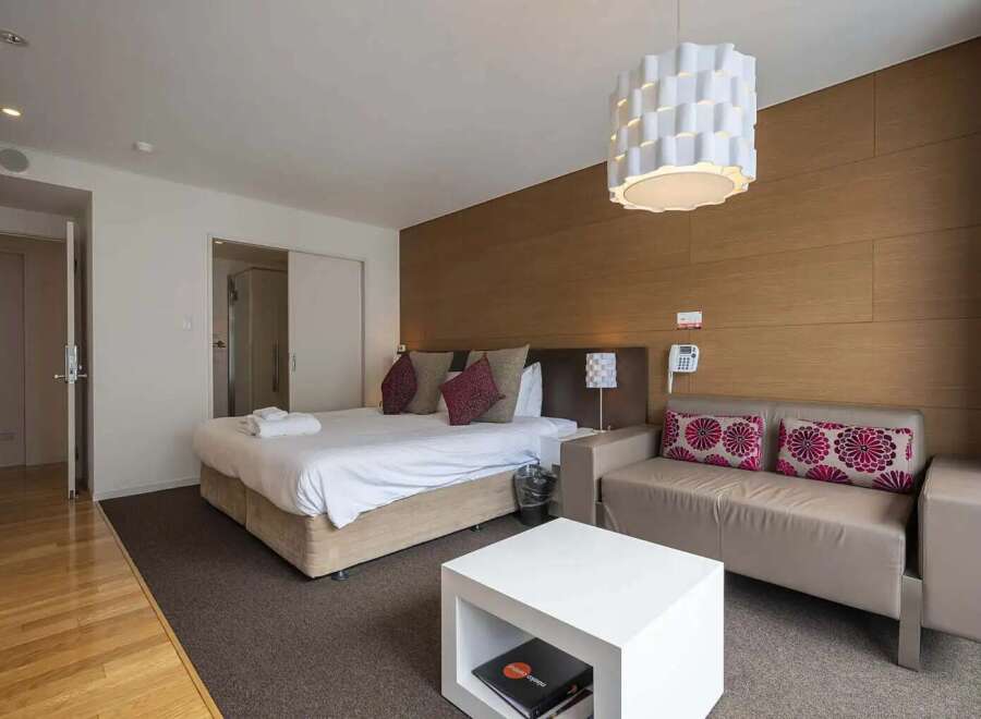 Modern hotel room featuring a comfortable king-size bed, stylish sofa, and a sleek coffee table.