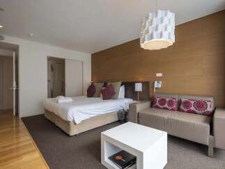 Modern hotel room featuring a comfortable king-size bed, stylish sofa, and a sleek coffee table.