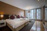 Modern hotel room with king-size bed, large windows offering city views, and stylish decor.