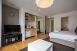 Modern studio apartment with mirrored sliding doors concealing a kitchenette and offering a bright, open feel.