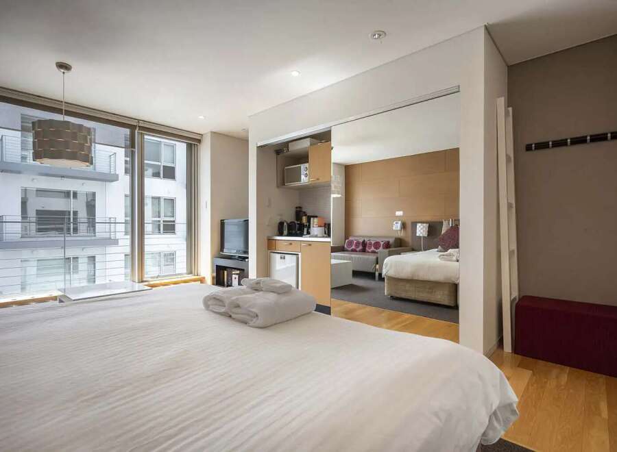 Modern studio apartment with mirrored sliding doors revealing a kitchenette and sleeping area.