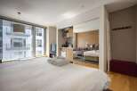 Modern studio apartment with mirrored sliding doors revealing a kitchenette and sleeping area.