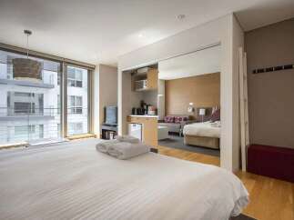 Modern studio apartment with mirrored sliding doors revealing a kitchenette and sleeping area.