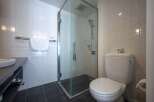 This modern bathroom boasts a sleek glass shower enclosure, a contemporary toilet, and stylish dark gray floor tiles.