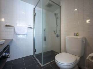 This modern bathroom boasts a sleek glass shower enclosure, a contemporary toilet, and stylish dark gray floor tiles.