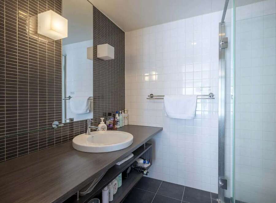 Modern bathroom with dark gray subway tile and white square tile, featuring a sleek floating vanity with under-sink storage.