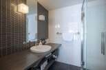Modern bathroom with dark gray subway tile and white square tile, featuring a sleek floating vanity with under-sink storage.