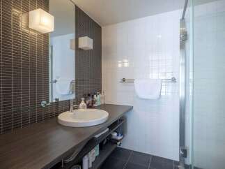 Modern bathroom with dark gray subway tile and white square tile, featuring a sleek floating vanity with under-sink storage.