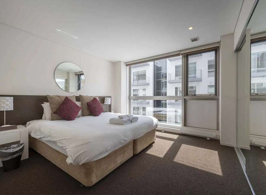 Luxurious hotel room with a king-size bed, plush pillows, and a large window offering stunning city views.