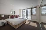 Luxurious hotel room with a king-size bed, plush pillows, and a large window offering stunning city views.