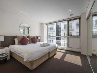 Luxurious hotel room with a king-size bed, plush pillows, and a large window offering stunning city views.