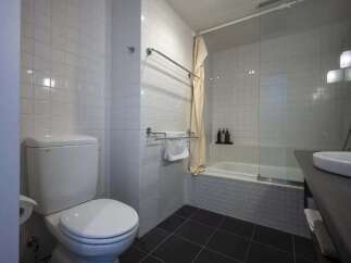 This modern bathroom boasts sleek white tile, a built-in bathtub with glass shower enclosure, and contemporary fixtures.