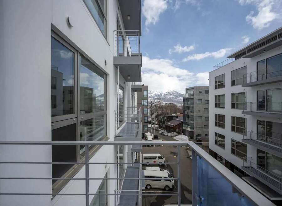 Modern apartment balcony overlooking mountain views and city.