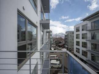 Modern apartment balcony overlooking mountain views and city.
