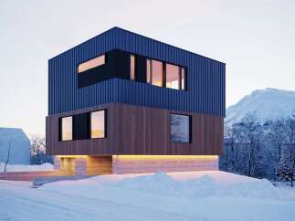 Stunning modern home nestled in a snowy mountain landscape.