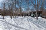 Stunning winter landscape showcasing a modern, dark-colored house nestled amongst snow-covered trees.