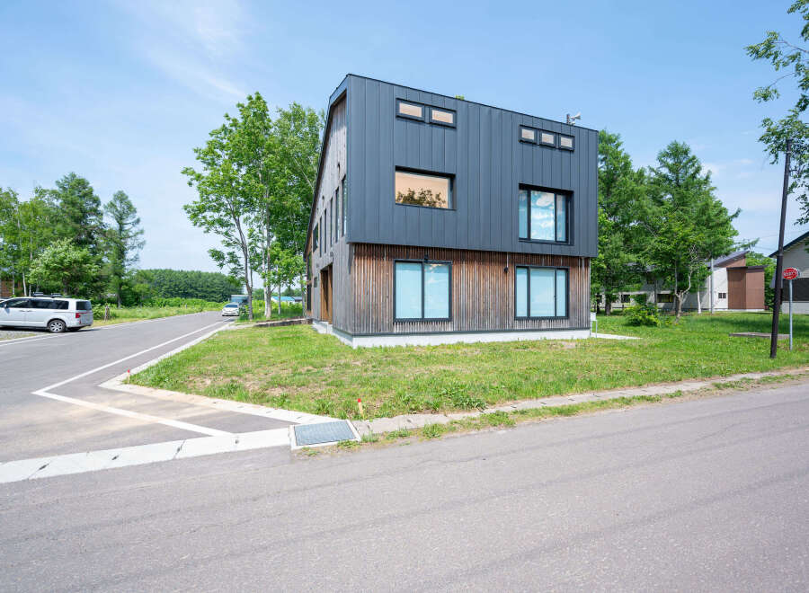 Modern house with dark gray metal siding and wood accents.