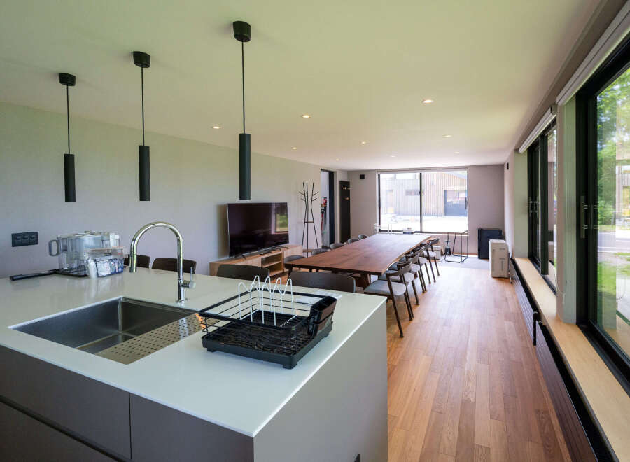 Modern open-plan living space with sleek kitchen island, hardwood floors, and floor-to-ceiling windows offering abundant natural light.