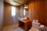 This modern bathroom boasts a sleek design with a glass shower enclosure, wooden wall paneling, and a stylish vanity.